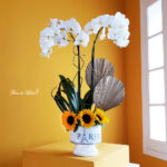Elegante orquídea con vibrantes girasoles en base Paris. - Image 5