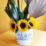 Elegante orquídea con vibrantes girasoles en base Paris. - Image 4